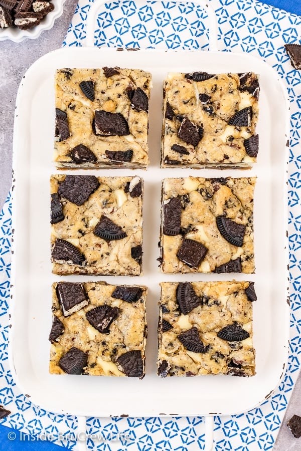 A white tray with squares of Oreo Chocolate Chip Cheesecake Bars on it.