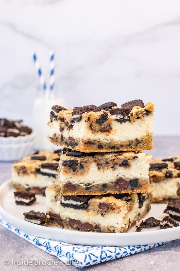 A white plate with three Oreo Chocolate Chip Cheesecake Bars stacked on it.
