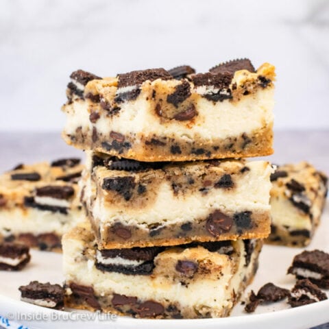 Three Oreo cookie cheesecake bars stacked on a white plate.