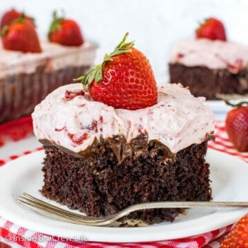 A white plate with a square of strawberry fudge poke cake on it and bite missing from the front of the cake