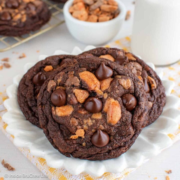 Three chocolate Butterfinger cookies on a white plate.