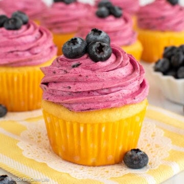Lemon blueberry cupcakes on a yellow towel.