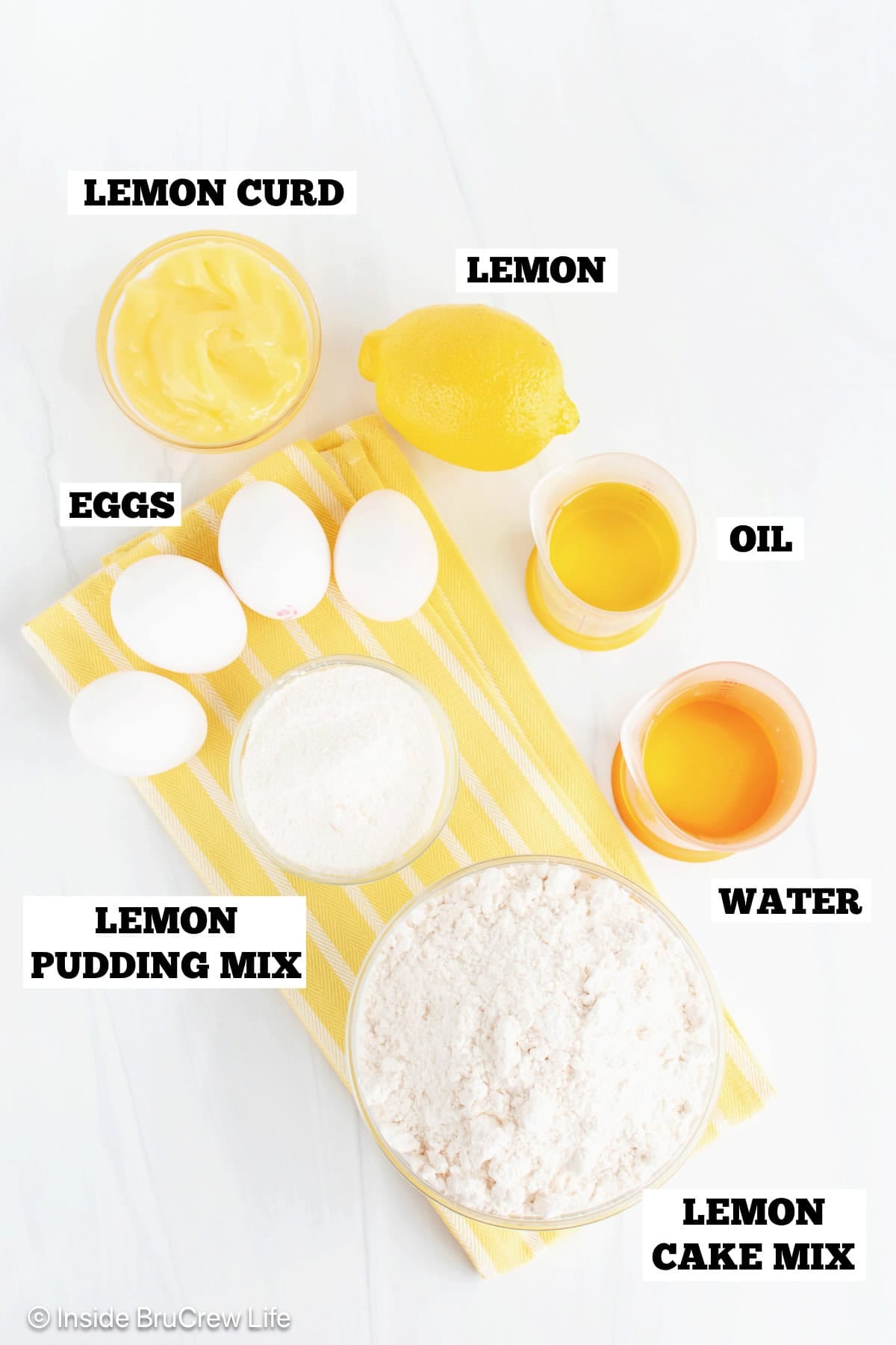 Ingredients for lemon blueberry cupcakes on a white board with labels.