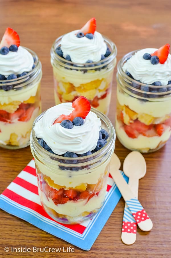 Four Lemon Fruit Parfaits with layers of cake, lemon mousse, and fresh berries topped with whipped cream and more berries