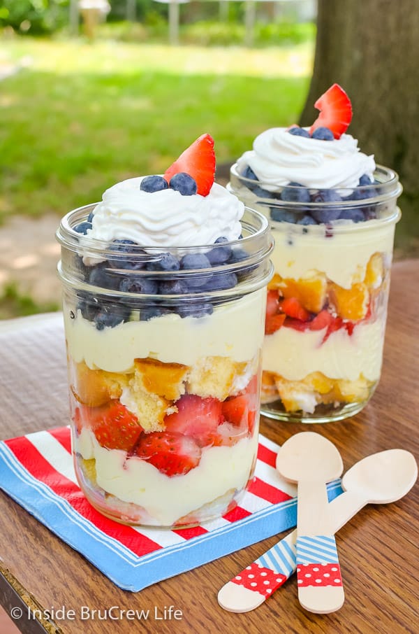 Two lemon fruit parfaits with layers of cake, filling, and fruit on a table outside