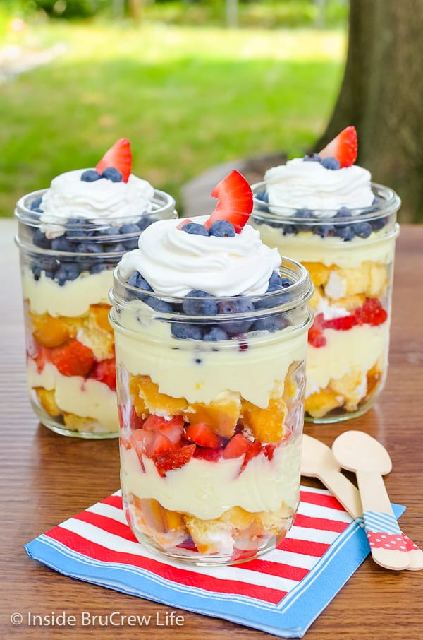 Three lemon fruit parfaits with layers of snack cakes, lemon mousse, and fresh fruit layered in each one