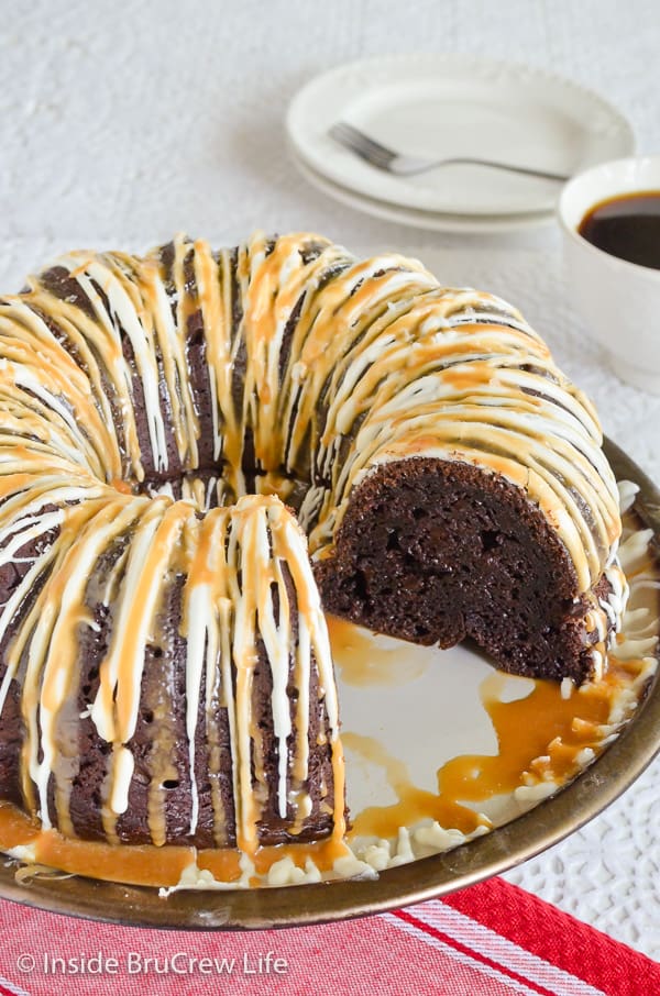 A mocha bundt cake on a plate drizzled with white chocolate and salted caramel.