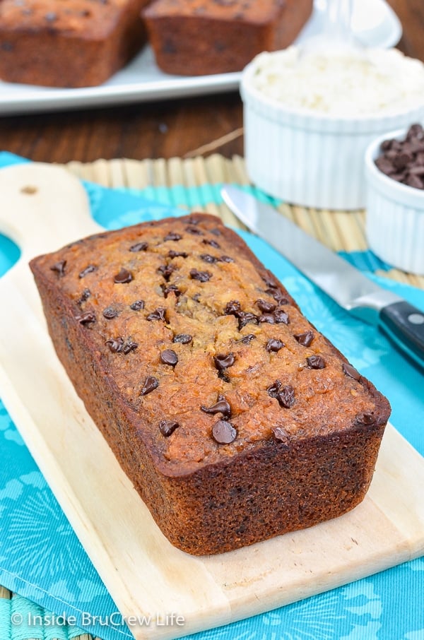 A loaf of healthy skinny banana bread on a cutting board and more loaves behind it.