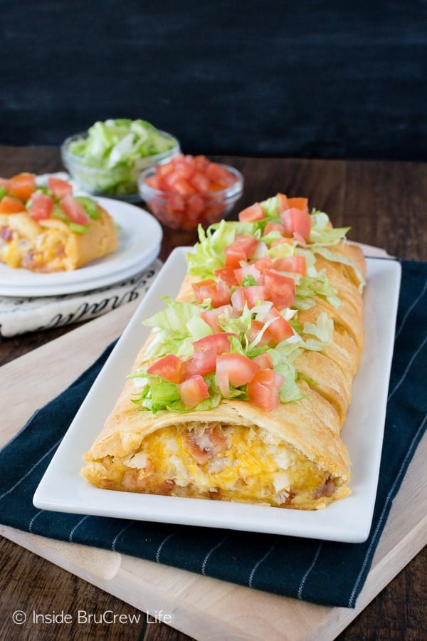 A blt chicken braid topped with lettuce and tomatoes on a white plate