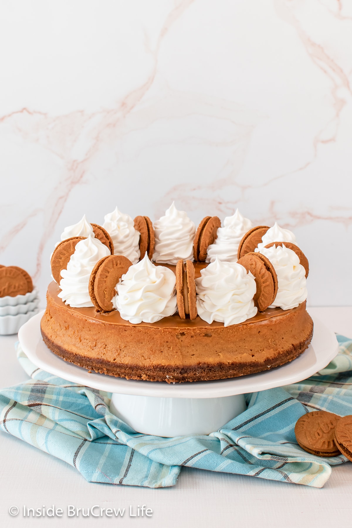 A full sized Biscoff cookie butter cheesecake on a cake plate.