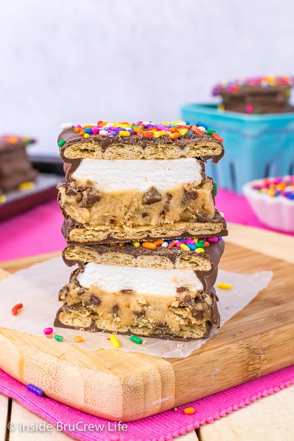 A no bake cookie dough s'mores cut in half and stacked on a wood tray facing forward so you can see the layers