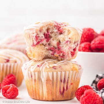 Two stacked muffins with a bite out of the top one showing fruit inside.
