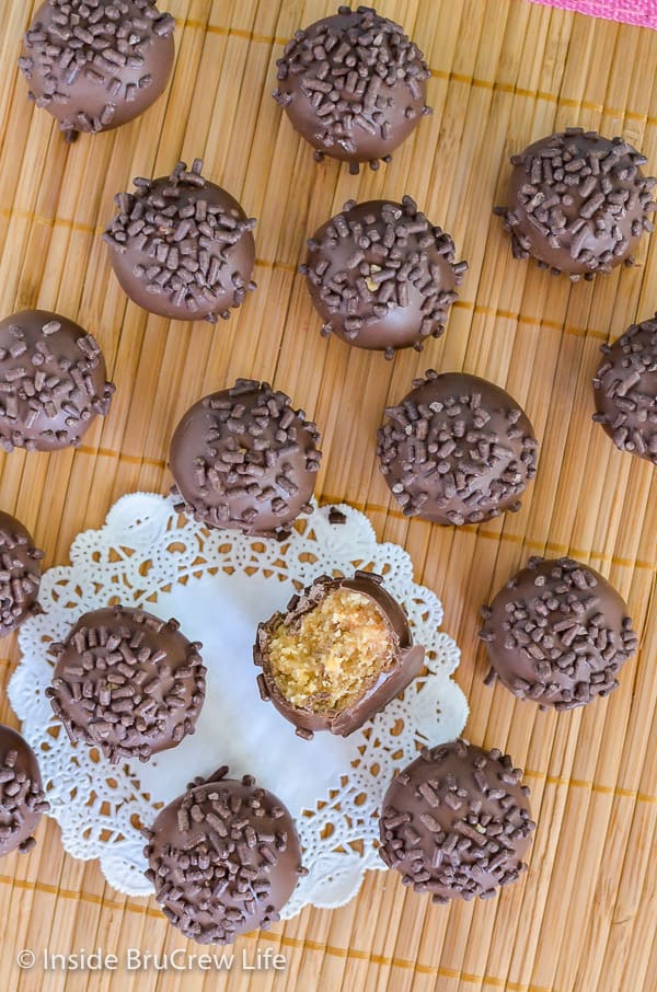 An overhead picture of butterfinger cookie dough truffles with chocolate sprinkles on top on a yellow wood placemat