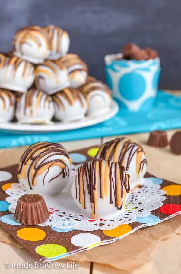 A white doily with three chocolate peanut butter cup cookie dough truffles drizzled with peanut butter and chocolate on it