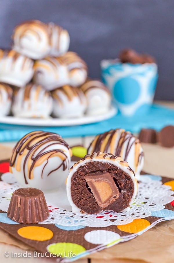 Three chocolate cookie dough truffles on a white doily with one cut in half to show a hidden peanut butter cup