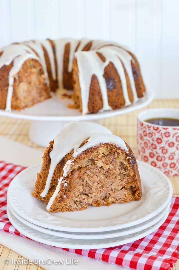 A stack of white plates with a slice of glazed apple bundt cake on it.