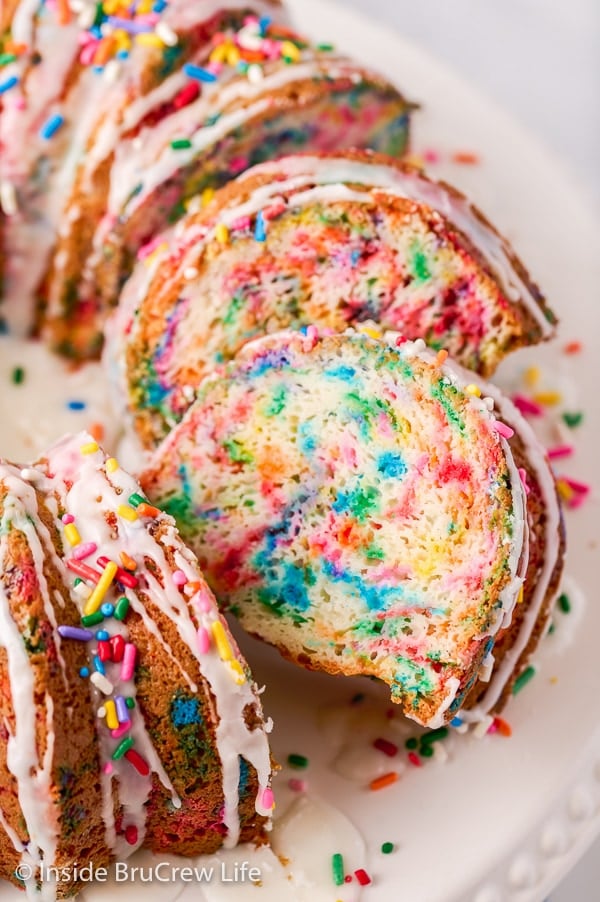 Slices of sprinkle bundt cake laying on a white cake plate.