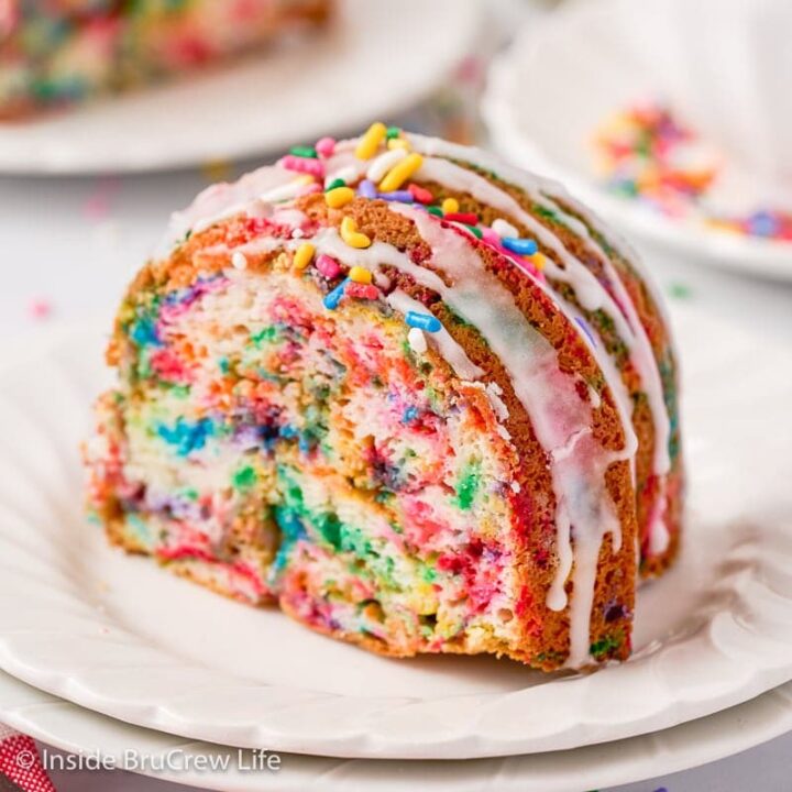 A slice of sprinkle cake on a white plate.