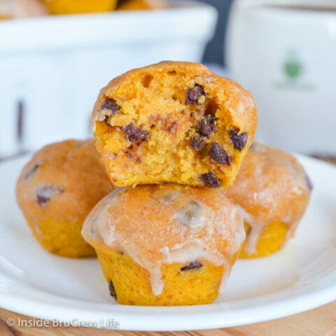 A white plate with a stack of mini pumpkin muffins on it.