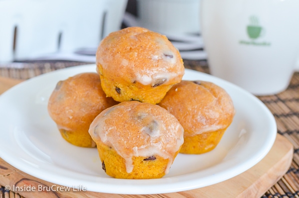 A white plate with glazed mini chocolate chip pumpkin muffins on it.