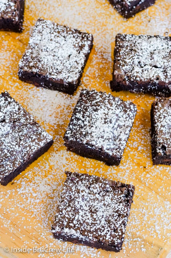 Overhead picture of a cutting board with squares of homemade brownies topped with powdered sugar