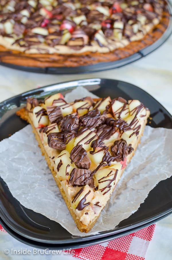 Peanut Butter Apple Pizza - a peanut butter cookie topped with apples and peanut butter cups makes a fun dessert! Easy recipe for fall parties! #peanutbutter #apple #cookiepizza #fall #cookie #peanutbuttercups