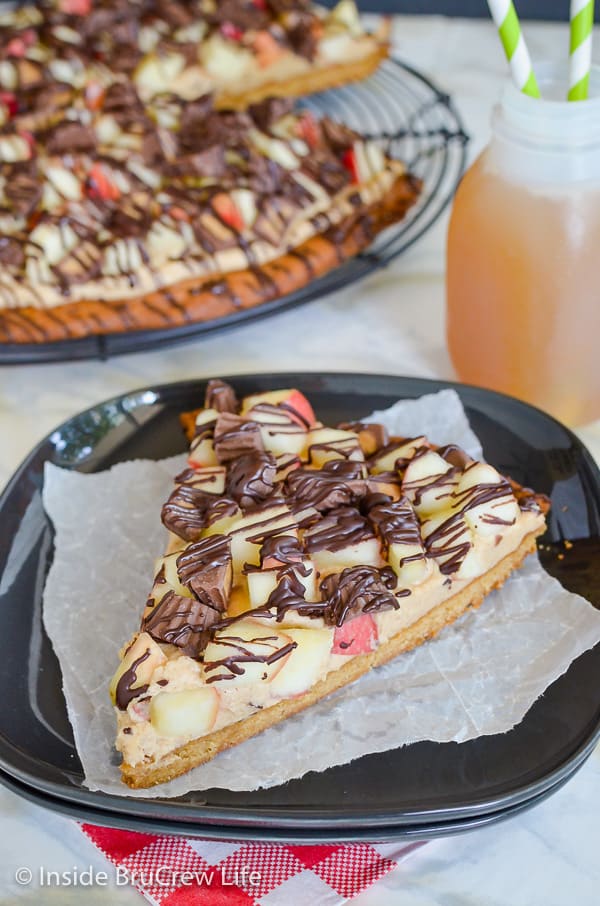 Peanut Butter Apple Pizza - a giant peanut butter cookie topped with apples and peanut butter cups is the perfect dessert! Make this easy recipe for fall parties! #peanutbutter #apple #cookiepizza #fall #cookie #peanutbuttercups