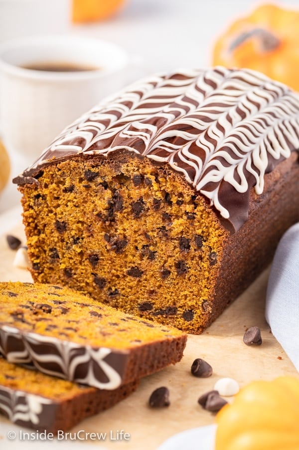 A loaf of chocolate chip pumpkin bread topped with a chocolate drizzle.