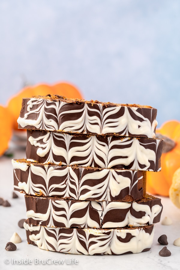 A stack of pumpkin bread slices topped with chocolate stacked on a white board.