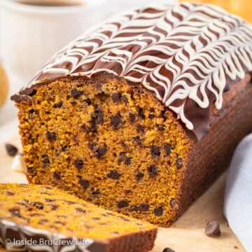 A loaf of pumpkin chocolate chip bread on a wooden board.