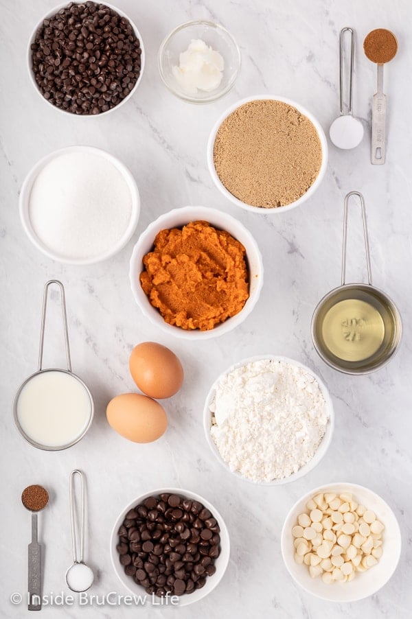 A white board with bowls of ingredients to make a pumpkin chocolate chip bread.