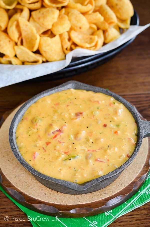 Overhead picture of a skillet filled with chicken queso dip and a basket of chips beside it.