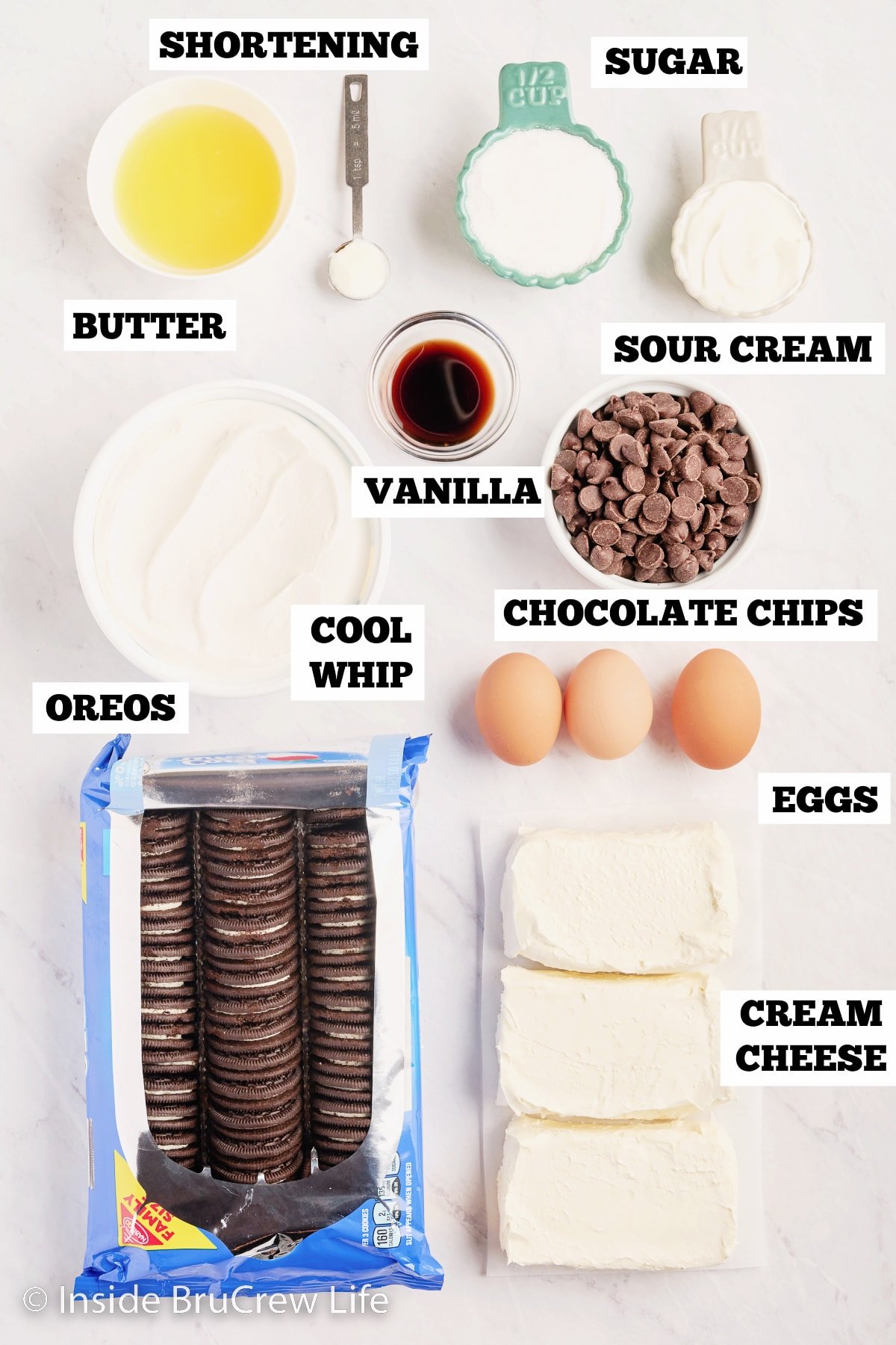 A white board with bowls of ingredients needed to make cheesecake bars.