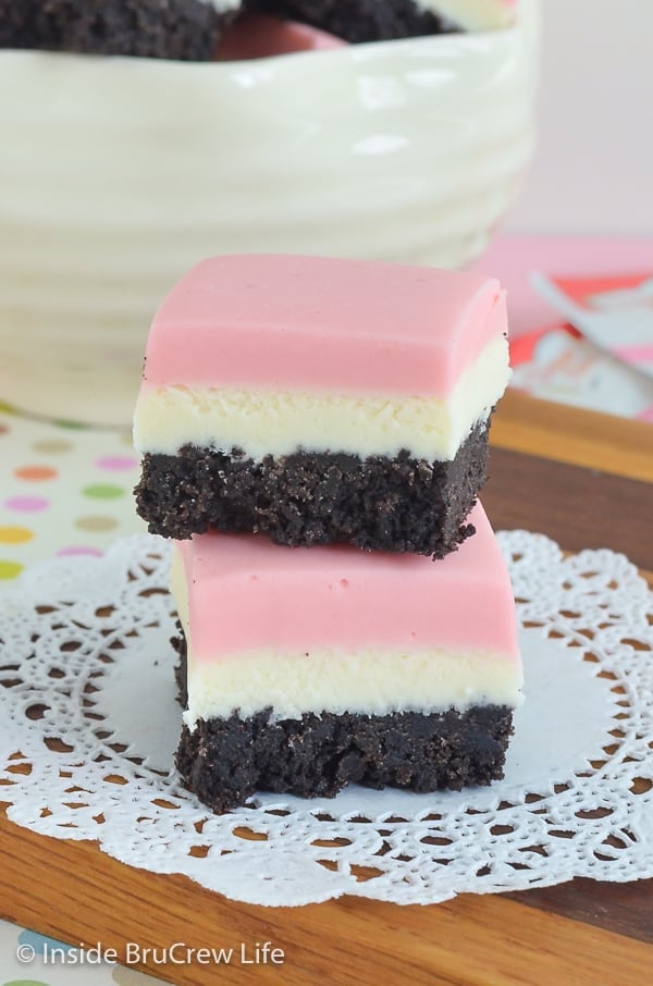 Two pieces of neapolitan fudge stacked on top of each other on a wooden board