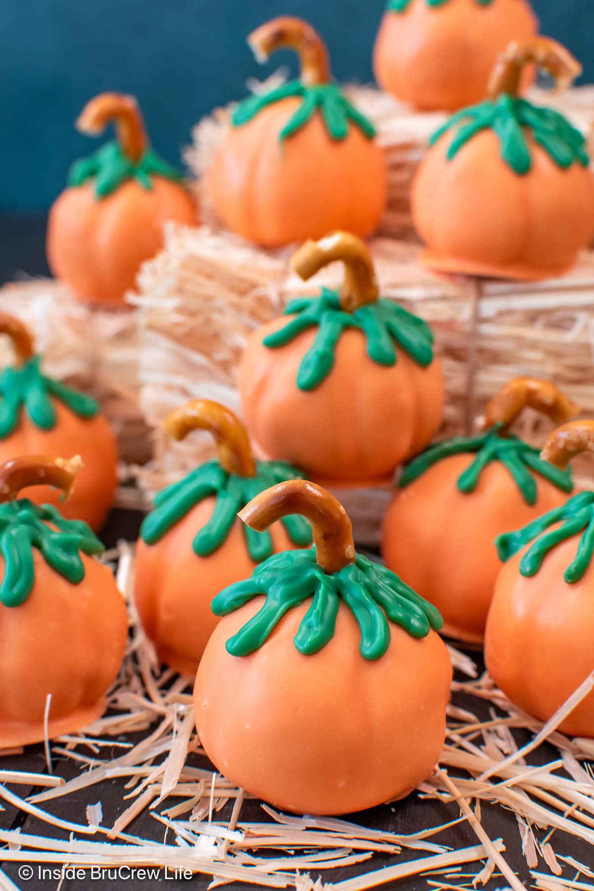 Peanut butter pumpkin balls on a board with hay.