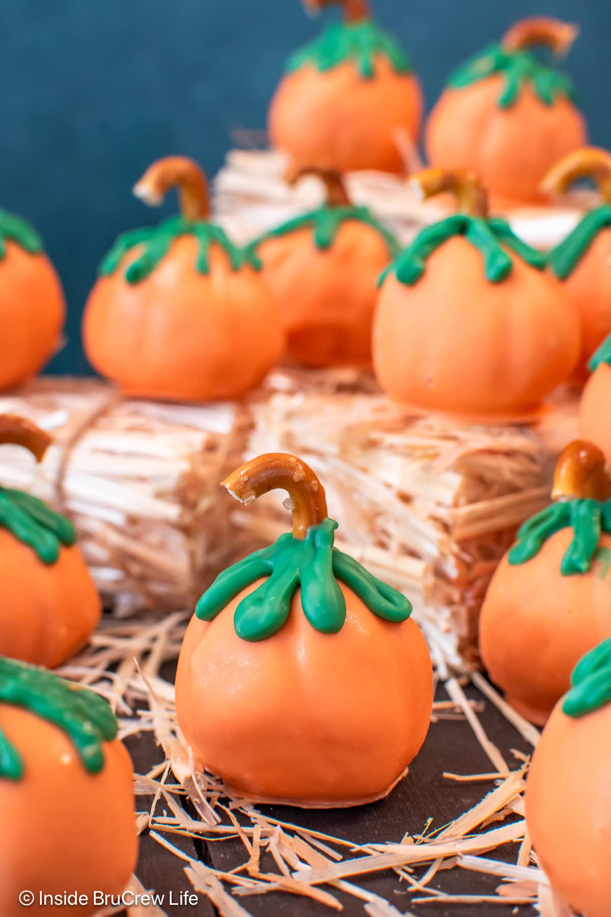 Orange candy pumpkins on a board with hay.