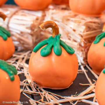 Orange candy pumpkins on a board with hay.