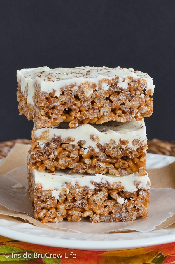 Three pumpkin spice treats topped with white chocolate stacked on top of a white plate.