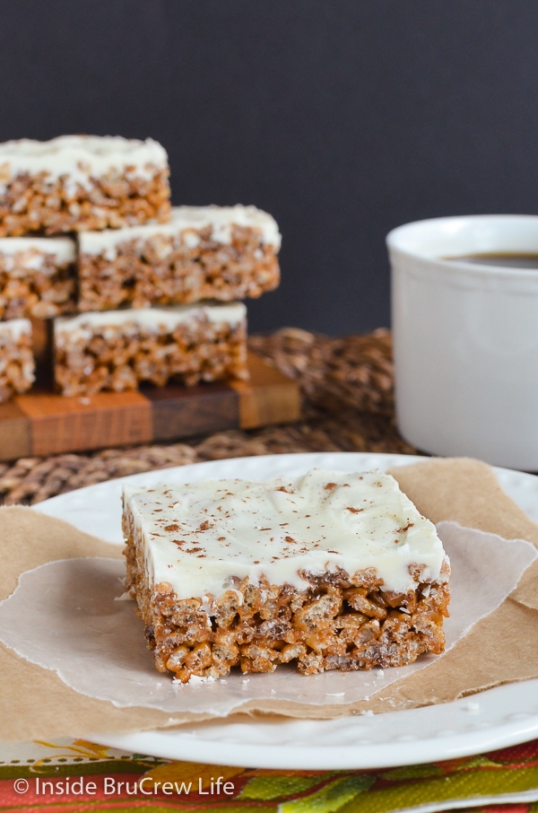 A white plate with one white chocolate topped pumpkin rice krispie treat on it.