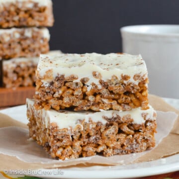 Two pumpkin spice rice krispie treats with white chocolate on a white plate.