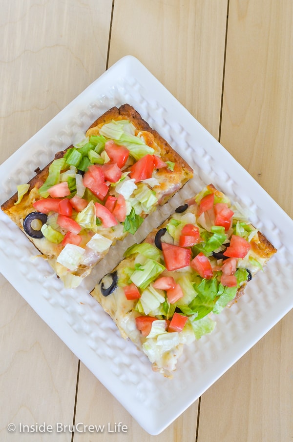 Overhead picture of a white plate with two squares of chicken bacon club pizza on it