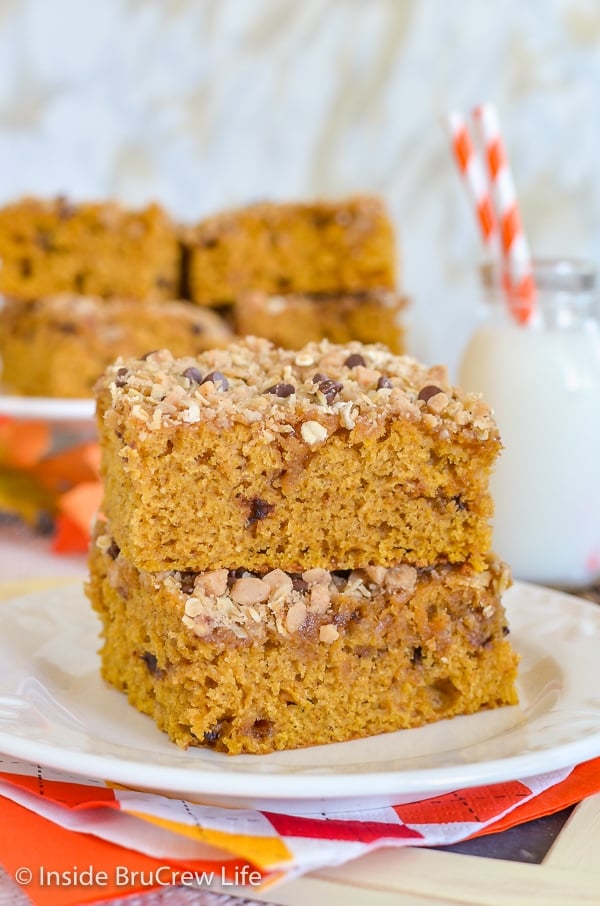 A white plate with two squares of pumpkin coffee cake with streusel stacked on it.