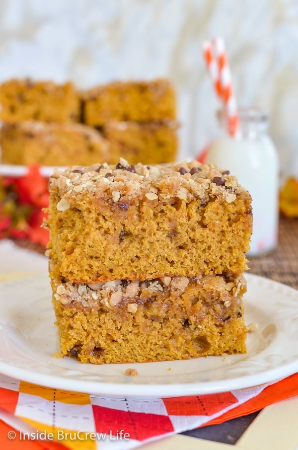 Two squares of pumpkin coffee cake with streusel stacked on a white plate