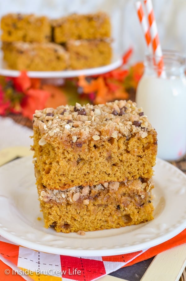 Two squares of pumpkin streusel coffee cake stacked on top of each other on a white plate