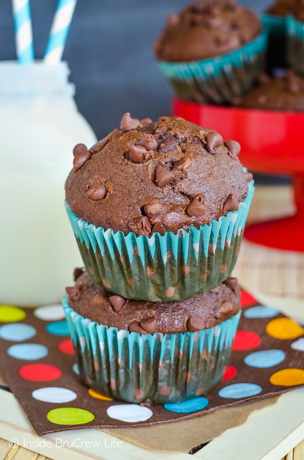 Two double chocolate banana muffins stacked on top of each other on a brown polkadot napkin.