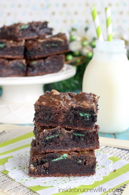 3 brownies stacked together and loaded with green mint cookies with milk in the background.