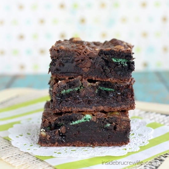 3 brownies stacked together and loaded with green mint cookies.