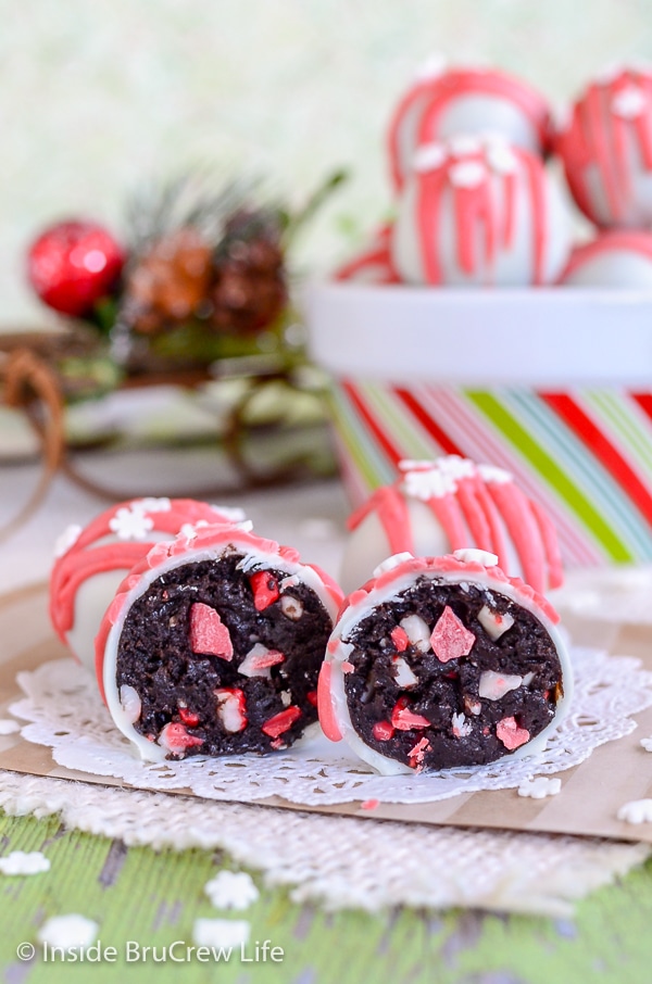 A white doily with a two peppermint crunch Oreo truffles cut in half and a bowl of truffles behind it