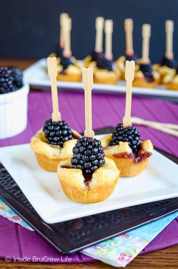 Blackberry Brie Bites on a white plate with more in the background.