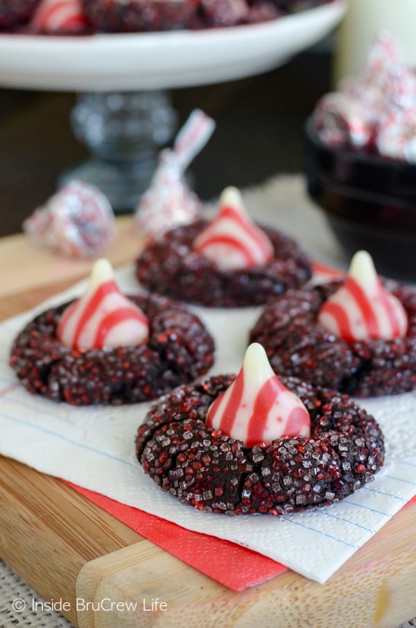 A white napkin with four chocolate kiss cookies with red and white sugar and candy cane kisses on them.